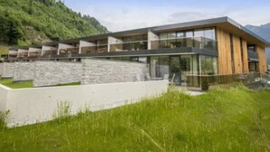 Ein modernes Gebäude mit Natursteinfassade, großen Glasfenstern und Holzverkleidung.