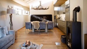 Ein modernes Wohnzimmer mit Sofa, Esstisch, Kamin und Küchenzeile.