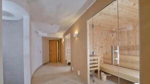 Ein modernes Interieur mit einer Holzsauna, einer Glastrennwand und einer neutralen Farbgestaltung.