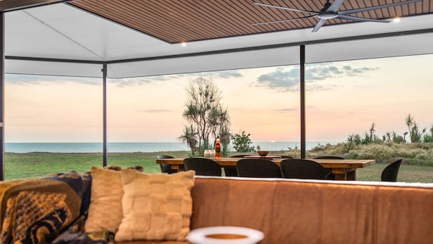 A covered outdoor seating area with a view of the sea at sunset. - Zenlux Mermaid Sunsets Beachfront Fishing Retreat (Dundee Beach)
