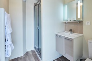 Une salle de bain moderne avec une douche à parois de verre, un lavabo blanc et un miroir au-dessus.