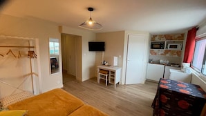 Un espai habitable compacte amb zona de menjador, petita cuina, televisió i seients amb sofà.