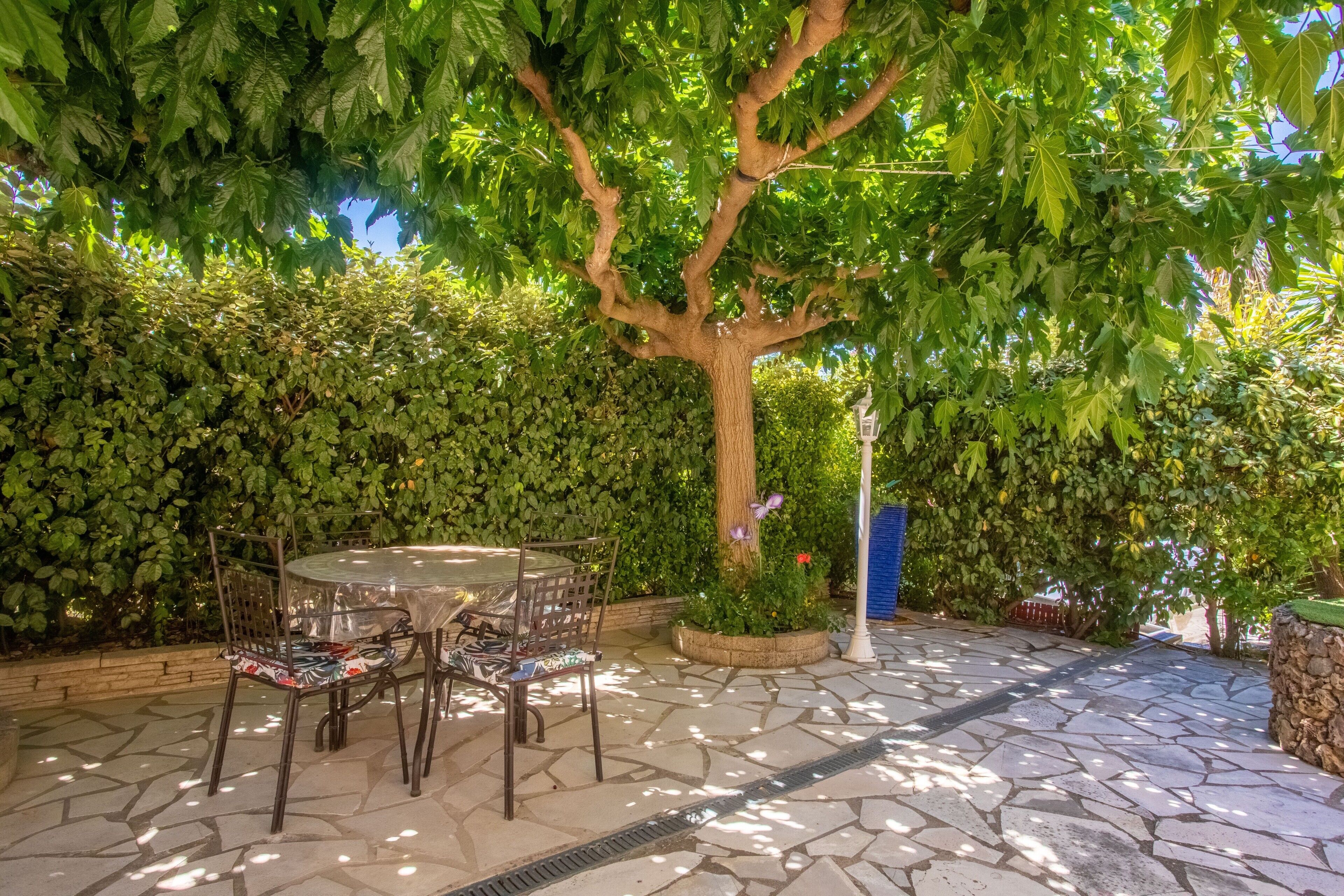 Une terrasse avec un sol en pierre, une table ronde et des chaises.