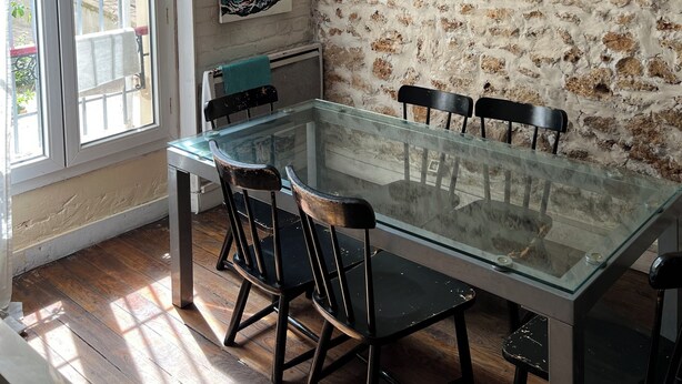 A dining area with a glass table, black chairs, a chandelier, a bull's head wall decoration, and a 'Hello' sign. - A cozy 35 m² apartment near Montmartre (Paris)
