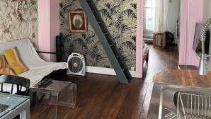 A loft-style room with a bunk bed, a fan, a clear glass table, and a staircase. - A cozy 35 m² apartment near Montmartre (Paris)
