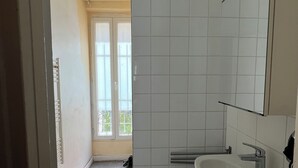 A bathroom with a sink, mirror, and tiled walls. - A cozy 35 m² apartment near Montmartre (Paris)