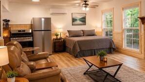 A cozy living room with a fireplace, a bed, a sofa, and a TV. - Studio on the River! (Noel)