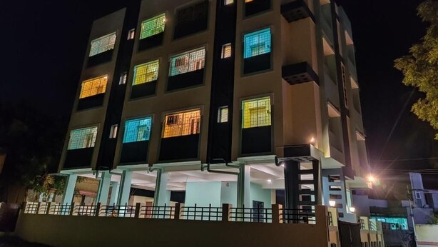 Un edificio de varios pisos con ventanas iluminadas y techo plano.