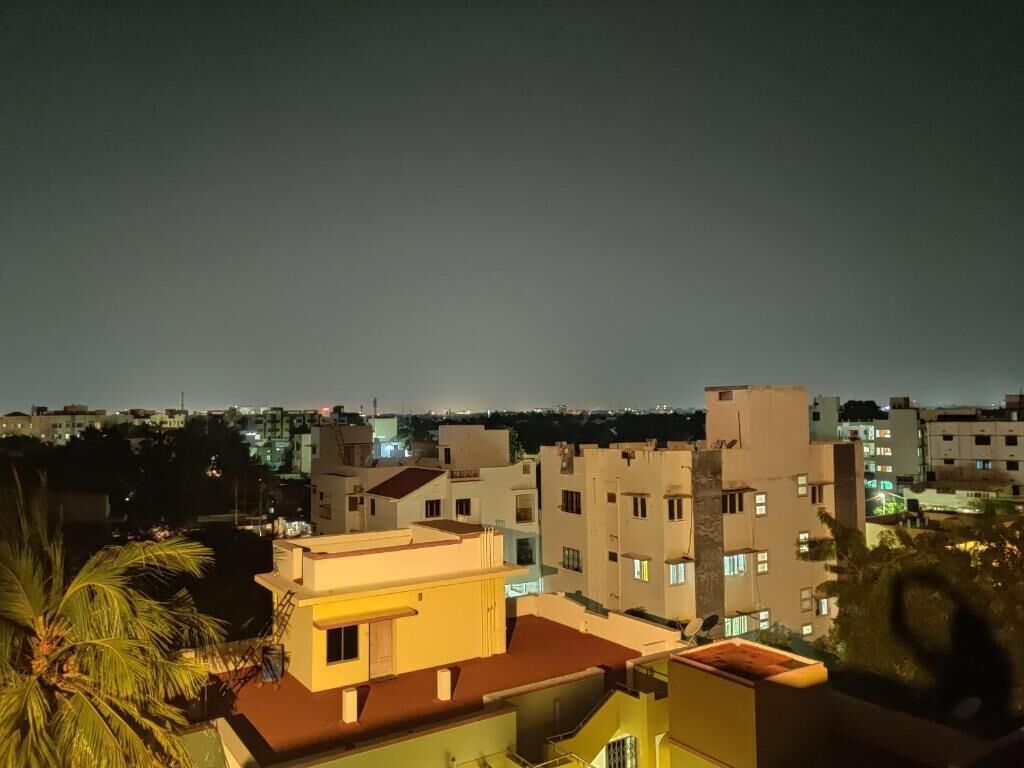 Vista nocturna de una zona residencial con varios edificios, algunos con balcones y antenas parabólicas visibles.