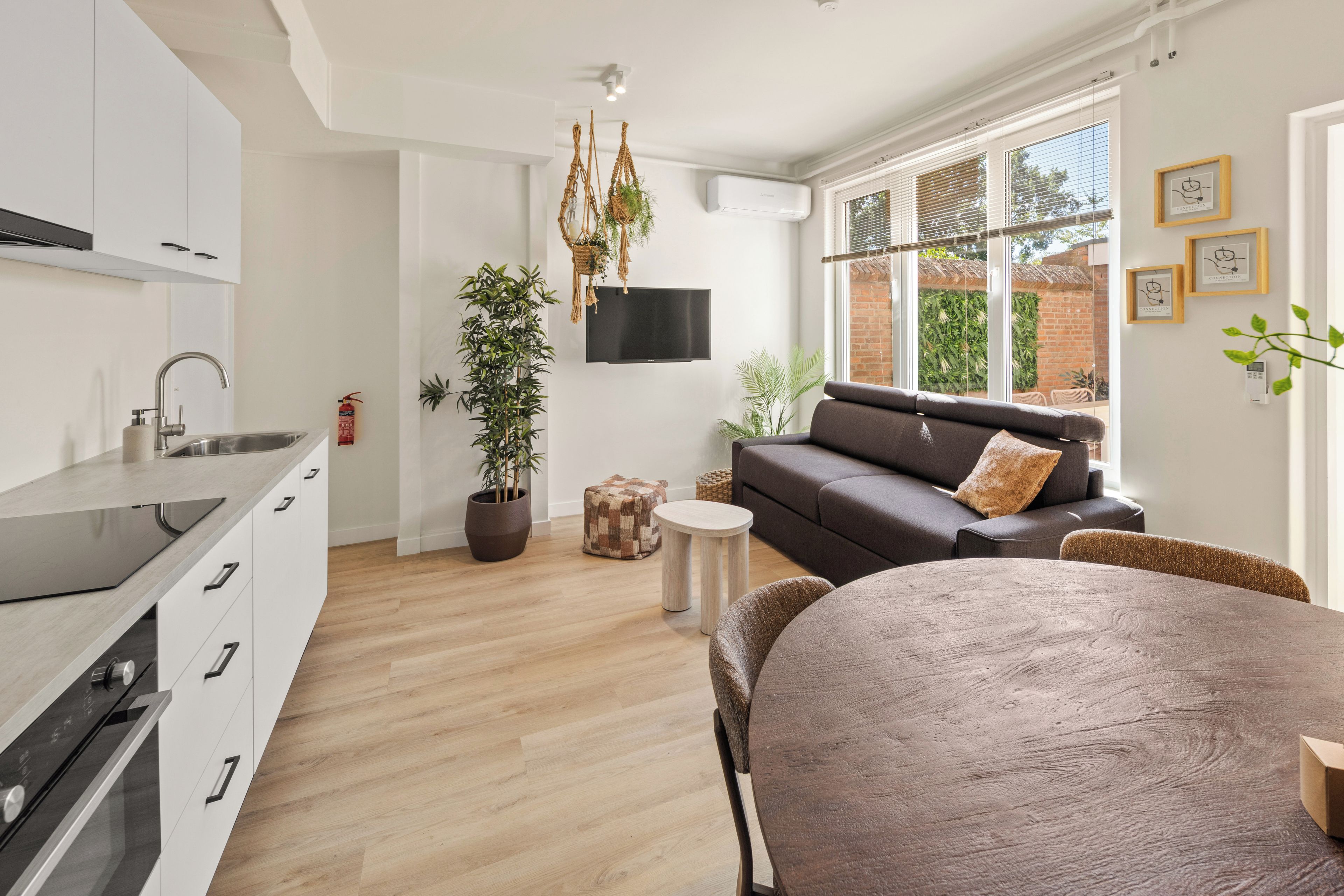 Et moderne køkken med indbygget ovn og spiseplads med en brun sofa og et rundt bord.