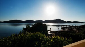 Ein friedlicher Seeblick mit einem sonnendurchfluteten Himmel, entfernten Bergen und einem Steg mit einem Gebäude.