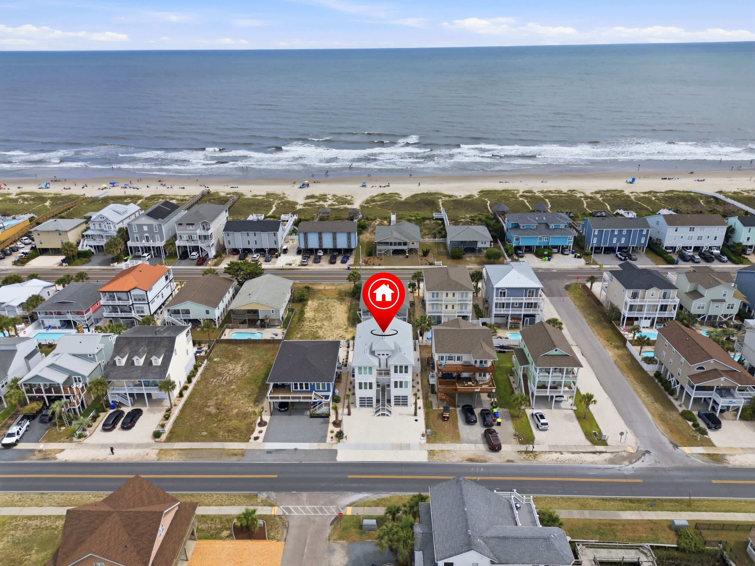 A coastal residential area with beachfront properties, a central road, and a prominent house with a swimming pool.