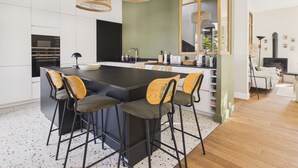 Een moderne keuken met een centraal eiland, barstoelen en hangende rieten lampen.