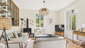 Een moderne woonkamer met een open haard, bank, poef en een televisie.