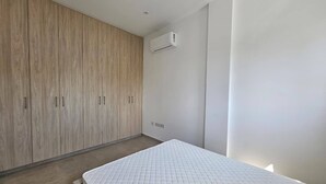 Ein Schlafzimmer mit einem Bett, einem Holzschrank und einer Klimaanlage.