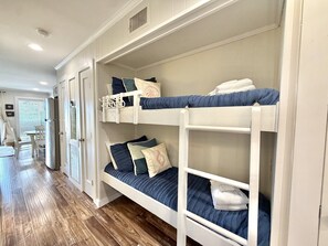 A room with bunk beds, a white door, and a wooden floor. - Ocean View - Ocean Villas B321- Professionally Managed by HHIB&T Vacation Rentals (Hilton Head Island)