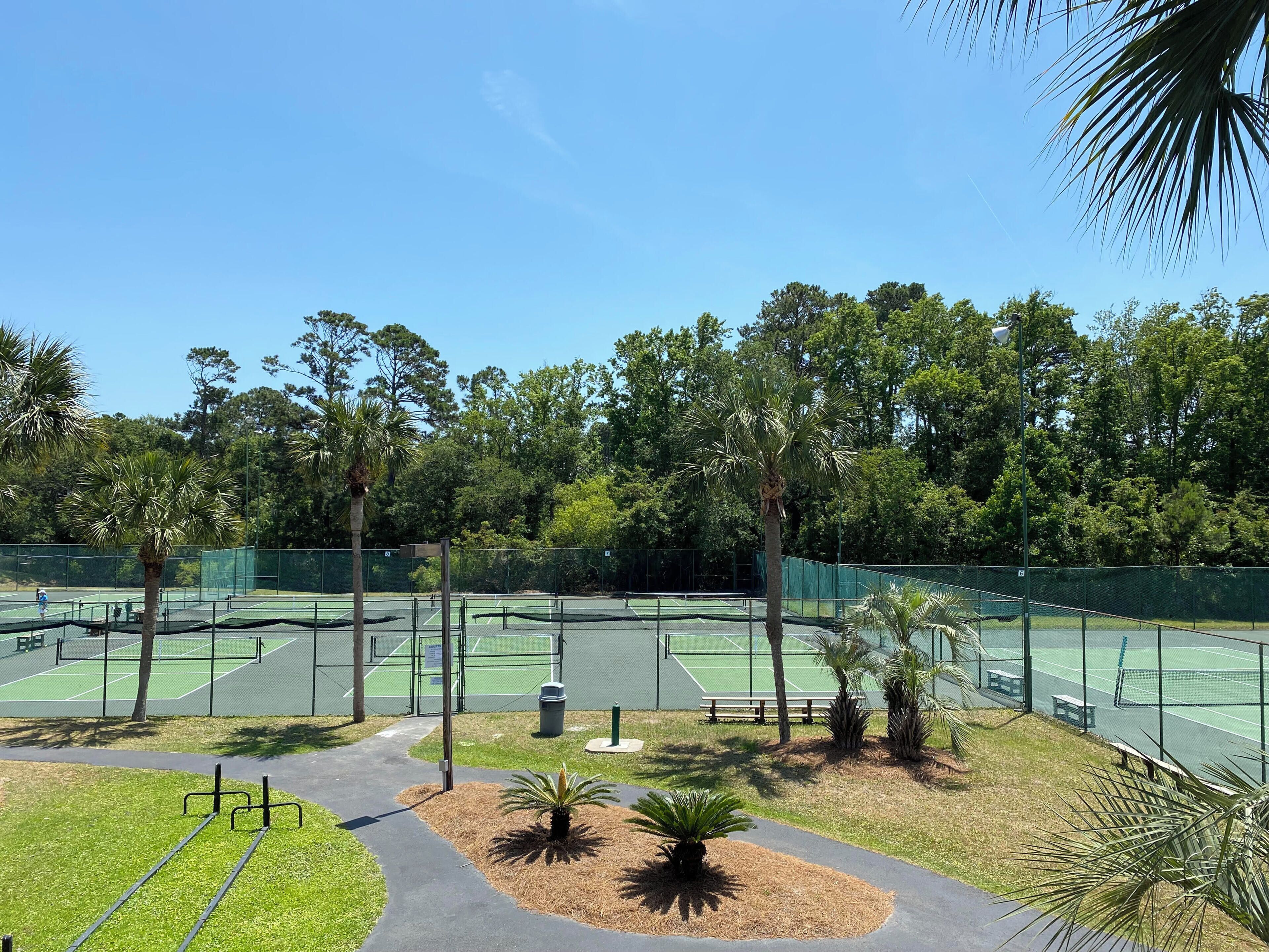 Een tennisbaan omringd door bomen en een pad.