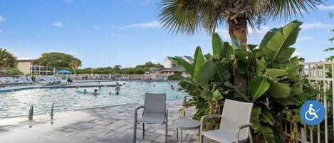 Zona de piscina con sillones de descanso, una palmera y señal de acceso para personas con discapacidad.