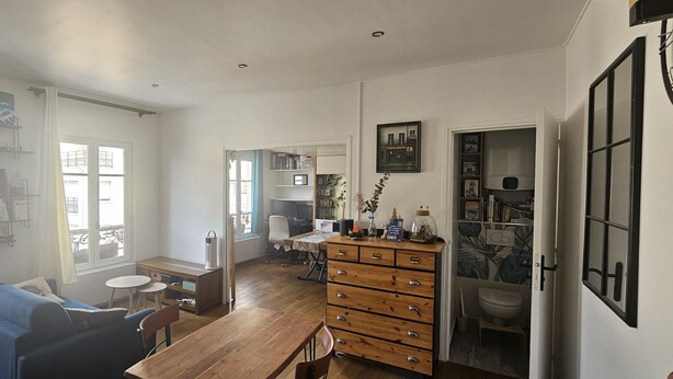 Uma sala espaçosa com sofá, mesa de jantar e aparador de madeira.