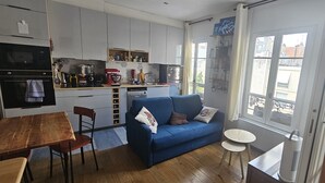 Um espaço compacto com cozinha compacta, sofá, mesa de jantar e uma pequena mesa redonda.