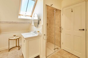 A bathroom with a shower, a sink, a mirror, and a small table. - Host & Stay | Topsail (Whitby)
