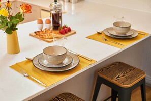 A dining area with a white table set for two, a vase with flowers, and a coffee maker in the background. - Host & Stay | Topsail (Whitby)
