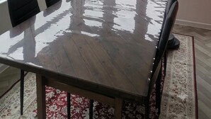 Ein Essbereich mit einem großen Tisch, Stühlen, einer Chandelier und großen Fenstern mit Blick auf einen Garten.