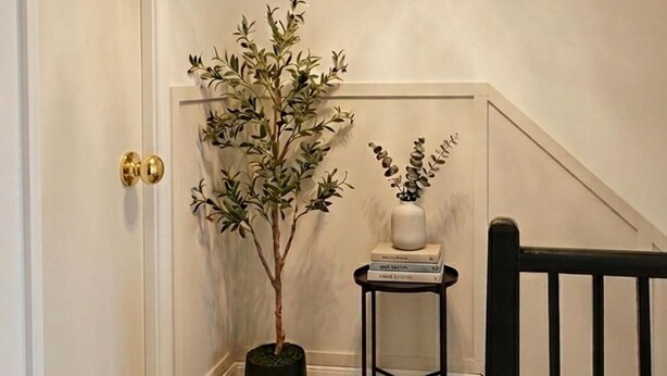 Ein Flur mit einer Kronleuchter, einem Blumentopf, einem kleinen Tisch mit Büchern und einer Treppe.