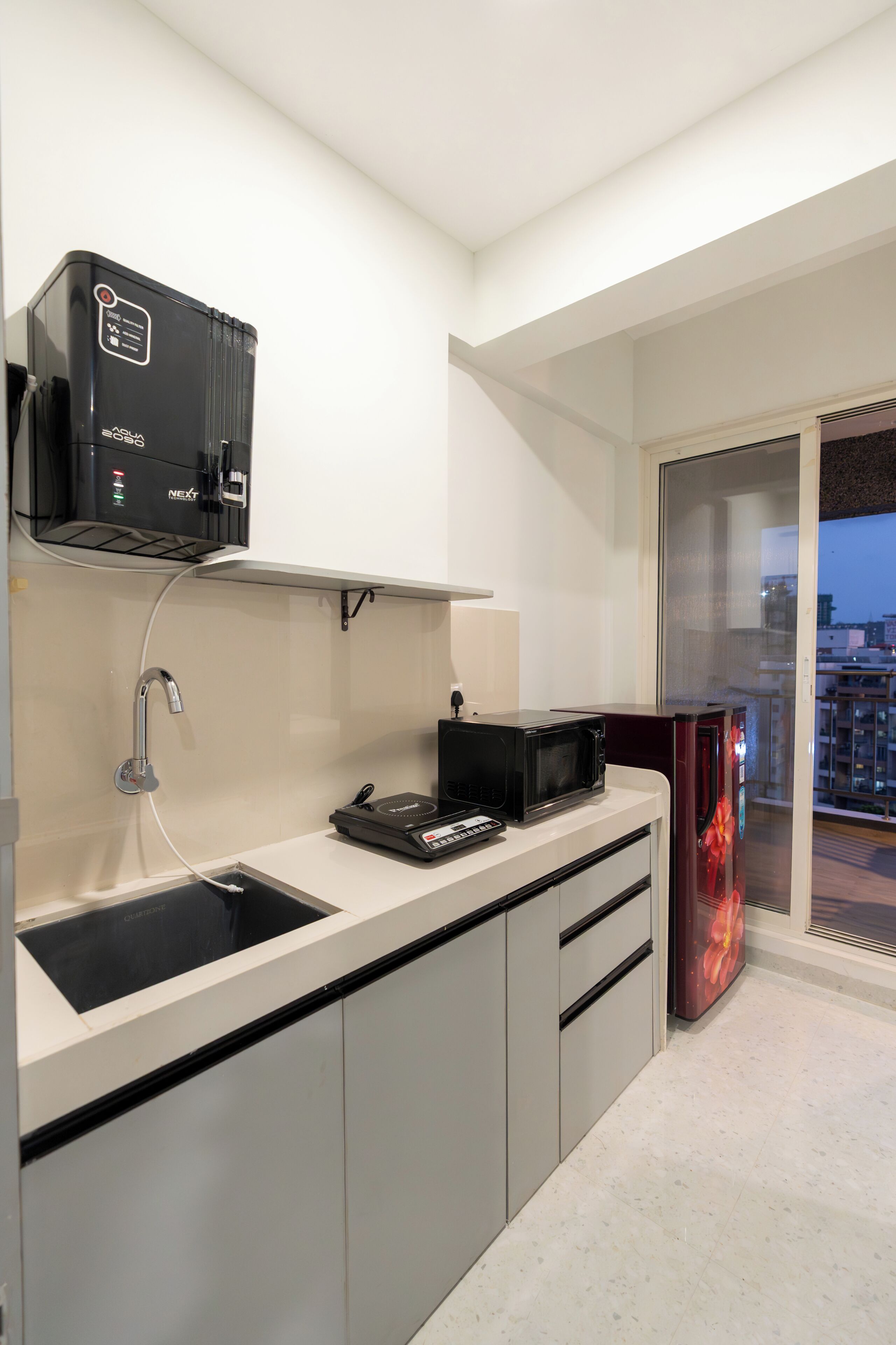 A modern kitchen with a microwave, a coffee machine, and a sink.