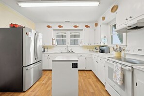 Una cocina moderna con armarios blancos, un refrigerador de acero inoxidable y una isla central con un fregadero.