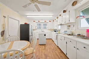 A compact kitchen with white cabinets, a refrigerator, a dishwasher, and a ceiling fan. - Fiddlers Roost - Creek Front - 4 Bedrooms (Pawleys Island)