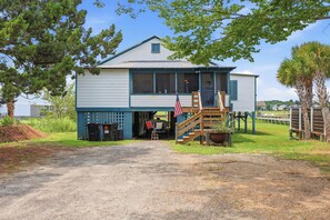 A two-story house with a porch and a flag. - Fiddlers Roost - Creek Front - 4 Bedrooms (Pawleys Island)