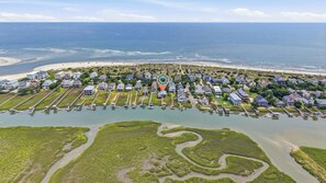 Vista aérea de una zona residencial costera con casas, una playa y un puerto deportivo.