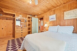 A wooden-paneled room with a bed, a wardrobe, and a desk with a lamp. - Fiddlers Roost - Creek Front - 4 Bedrooms (Pawleys Island)