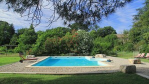 A rectangular swimming pool with a pebble border, surrounded by a grassy area and trees. - Country House “Gîte Noisettes” with Shared Pool, Private Terrace, and Wi-Fi (Saint-Didier-sous-Aubenas)