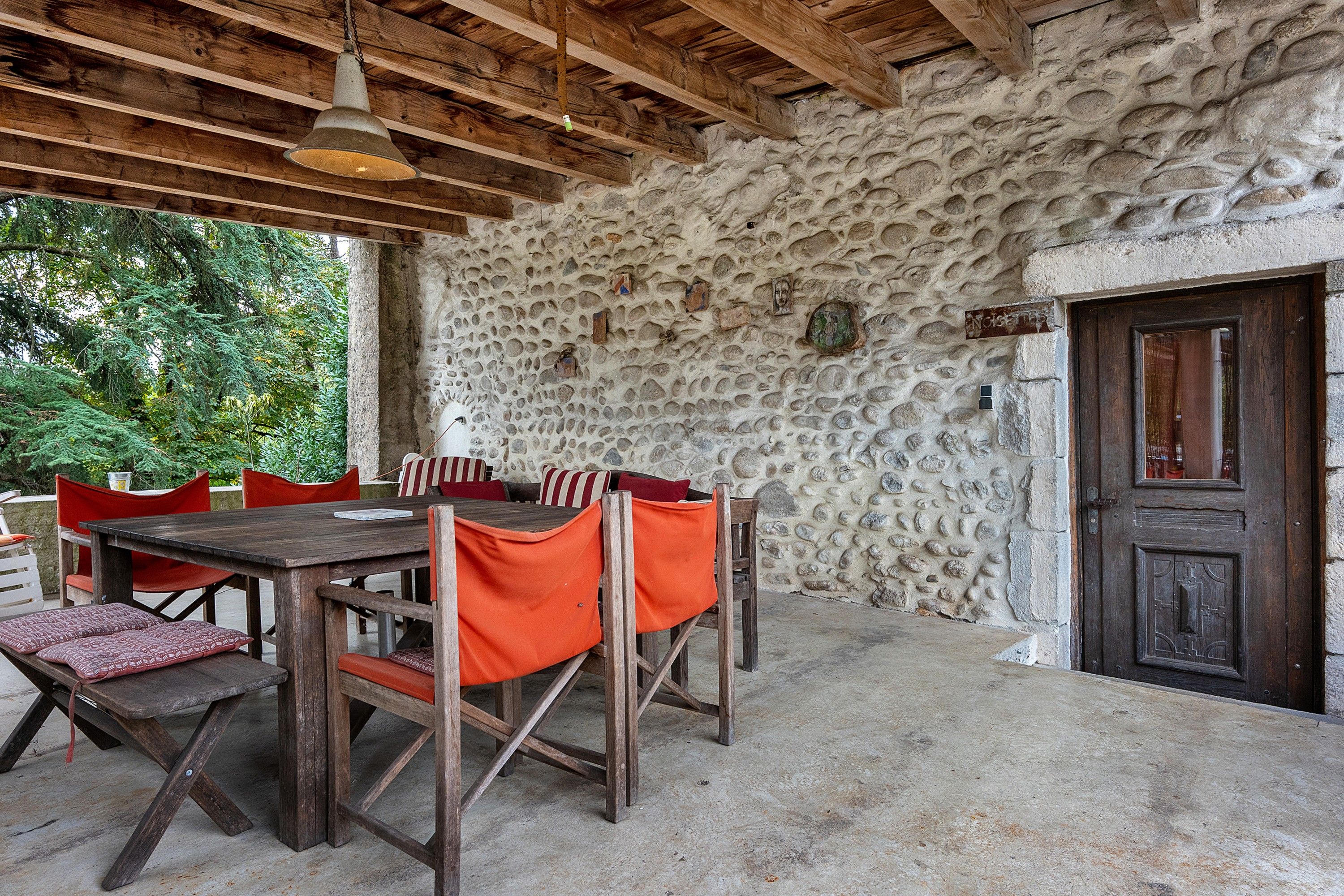 Un espace extérieur aménagé pour les repas, avec un mur en pierre, des meubles en bois et une porte.