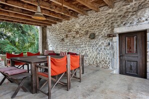 An outdoor dining area with a stone wall, wooden furniture, and a door.