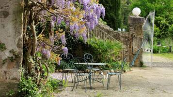 A garden with a table and chairs, a stone wall, and a gate.