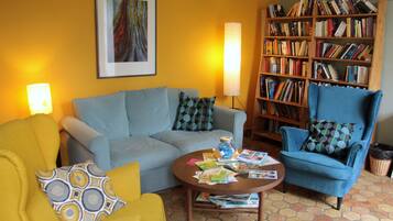 A living room with a sofa, armchair, and a bookshelf filled with books.