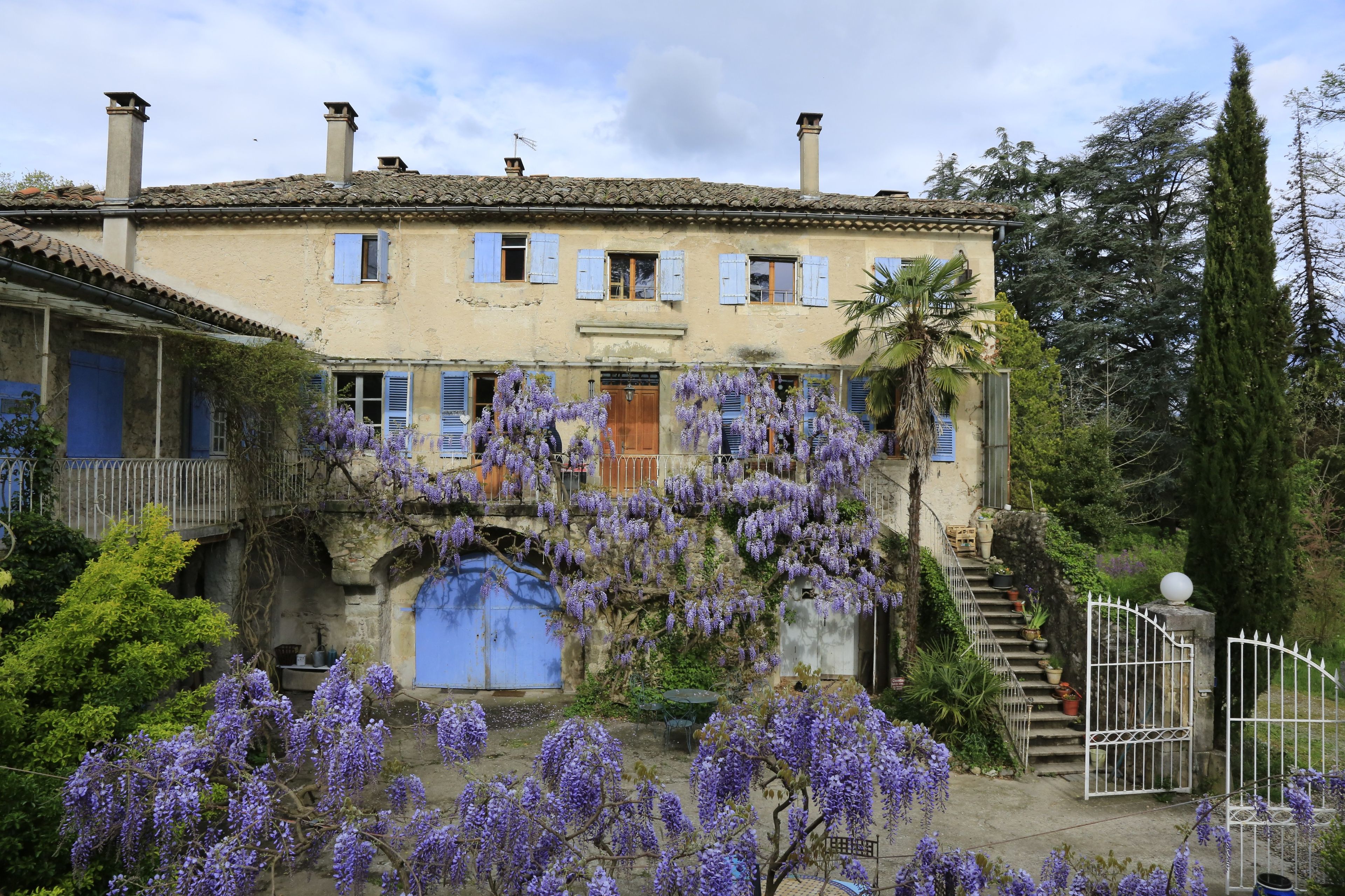 A traditional building with a stone archway, a wooden door, and a staircase leading to a gated entrance.