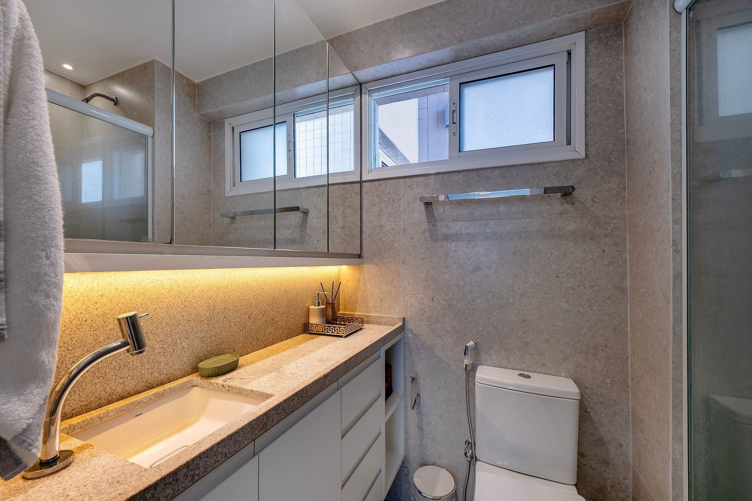 Un baño moderno con cabina de ducha de vidrio, un lavabo con grifo cromado y un inodoro.
