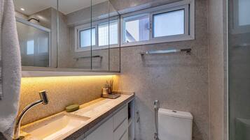 Un baño moderno con cabina de ducha de vidrio, un lavabo con grifo cromado y un inodoro.