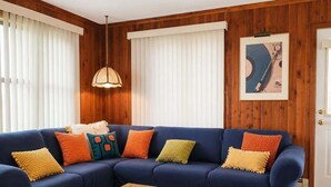 A living room with a blue sofa, colorful pillows, a glass coffee table, and a multicolored rug. - Beach front 3 Bedroom home 3 Home (Milton)
