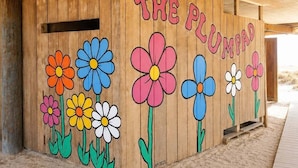 A wooden structure with colorful flower murals and the text 'THE PLUMPAD.' - Beach front 3 Bedroom home 3 Home (Milton)