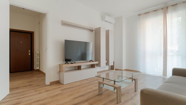 A modern living room with a flat-screen TV, a glass coffee table, and a beige sofa. - A cozy 82 sqm apartment, ideal for 5 people, located on the first floor of a building with an elevator.The property is situated in Comasina, a residential area rich in amenities and green spaces, right next to Parco Nord Milano.The Comasina M3 metro stat (Milan)