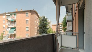 A balcony with a view of adjacent buildings, a metal railing, and a door leading to an interior space. - A cozy 82 sqm apartment, ideal for 5 people, located on the first floor of a building with an elevator.The property is situated in Comasina, a residential area rich in amenities and green spaces, right next to Parco Nord Milano.The Comasina M3 metro stat (Milan)
