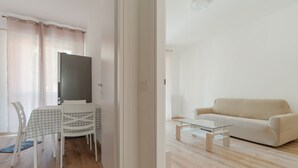 A modern living room with a glass coffee table, a beige sofa, and a dining area with a checkered tablecloth and chairs. - A cozy 82 sqm apartment, ideal for 5 people, located on the first floor of a building with an elevator.The property is situated in Comasina, a residential area rich in amenities and green spaces, right next to Parco Nord Milano.The Comasina M3 metro stat (Milan)