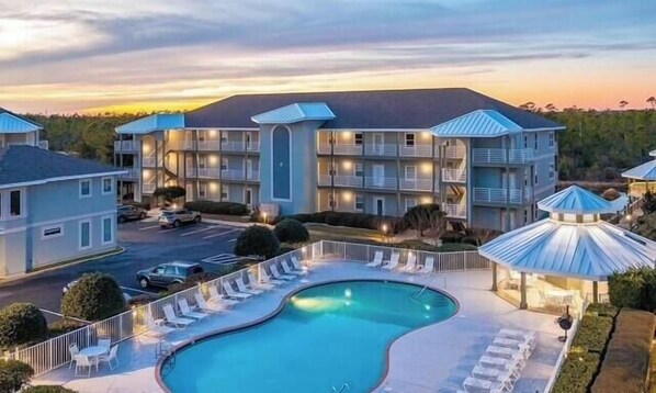 A hotel with a swimming pool, multiple balconies, and a parking area. - Romar Lakes 104a 2 Bedroom Condo (Orange Beach)
