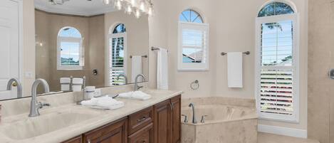 Une salle de bain avec deux éviers, un meuble-lavabo, une baignoire et un ventilateur de plafond.