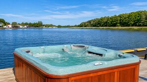 A hot tub on a wooden deck by a lake with a clear sky. - Boat House for 7 With Jacuzzi (Dziwnów)